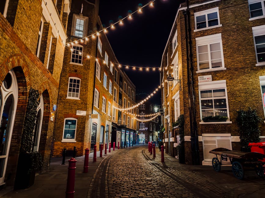 Illuminated cobblestone street in Soho, London with string lights and historic b