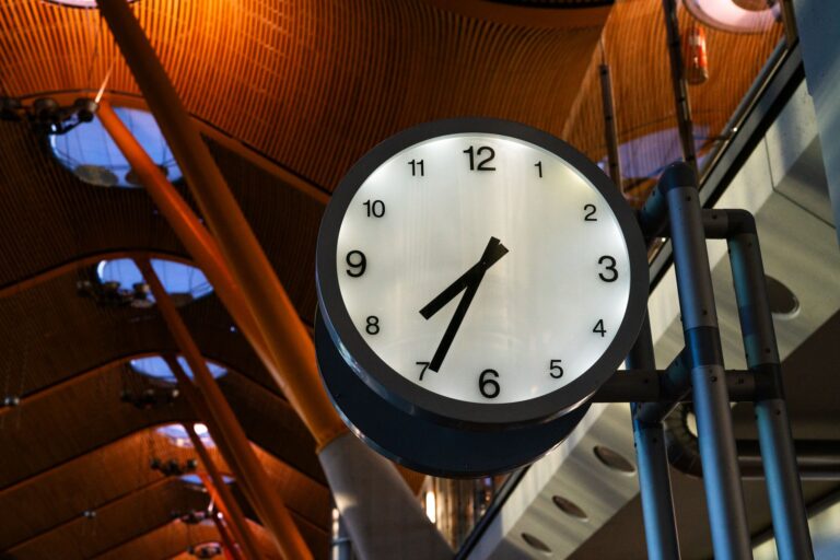 Reloj de una terminal de aeropuerto con viajeros al fondo