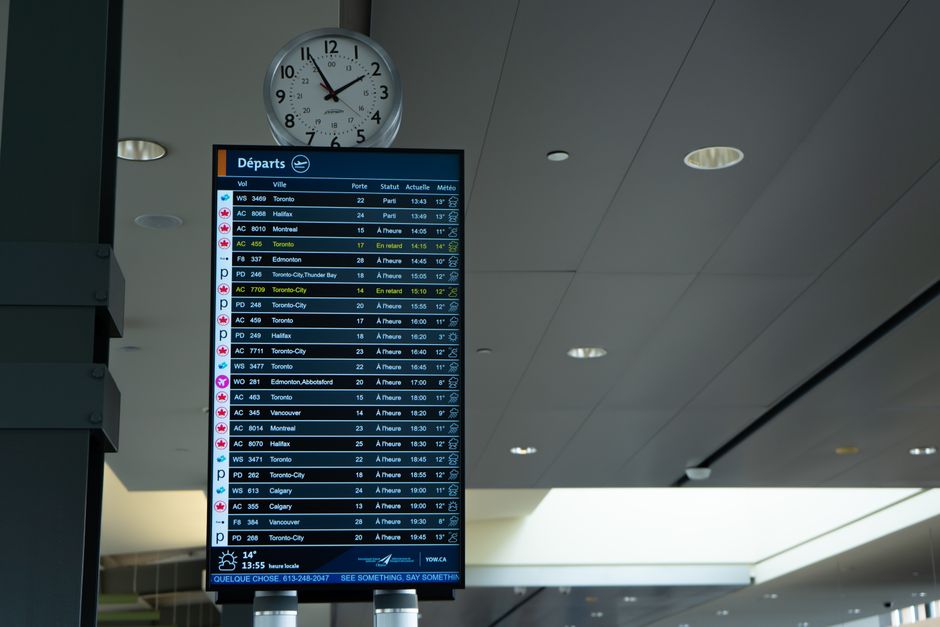 Panel de salidas y reloj en la terminal de un aeropuerto